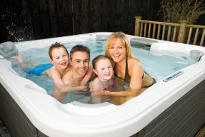 A family of four poses for a picture while in their backyard hot tub