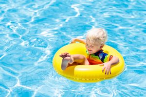 A little boy in a yellow inflatable pool float in a swimming pool