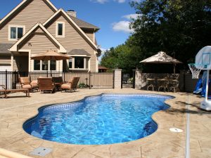 In-ground swimming pool with large patio area behind home