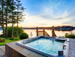 Picture of a hot tub on a deck with trees and a lake in the background